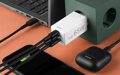 A smartphone, headphones and laptop are charged using a multi-port GaN charger.