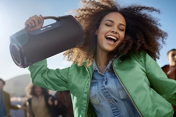 Mujer celebra con entusiasmo con altavoz Bluetooth® Hama "Mate Pro"