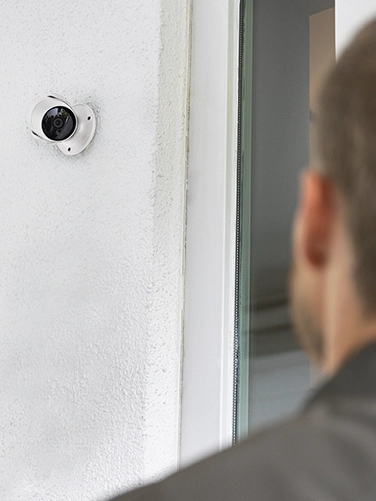 Un hombre frente a una puerta de entrada y filmado por la cámara de vigilancia de Hama.
